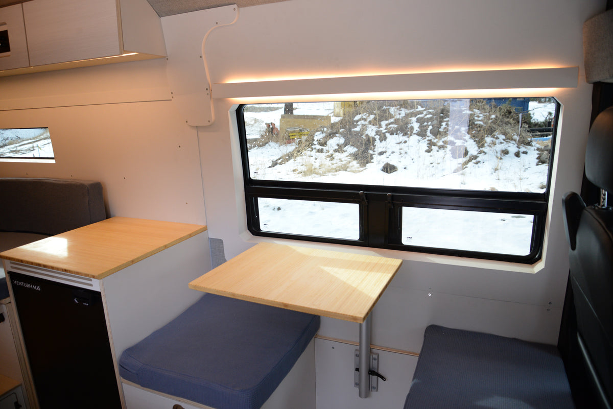 Small dining area inside a vehicle with a window showing a snowy landscape.